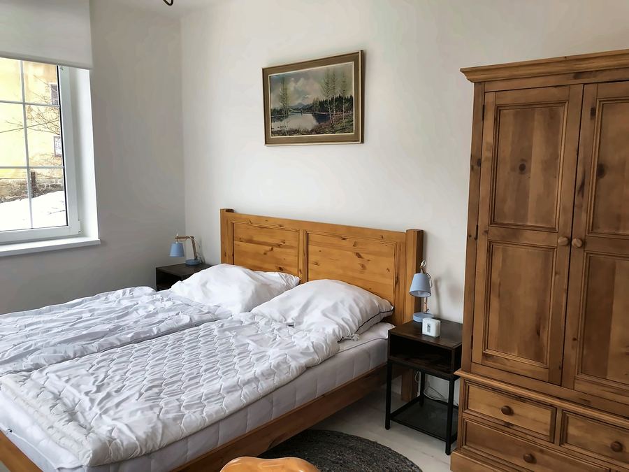 Ložnice s dřevěnou manželskou postelí a skříní