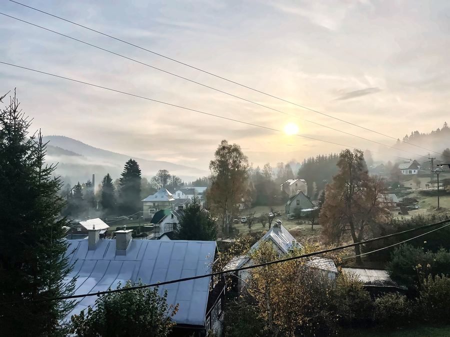 Ranní mlha nad údolím a střechami, vychází slunce